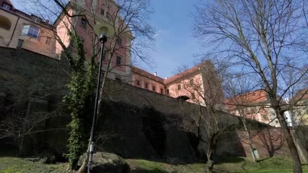 Historické budovy města Olomouce stojící na vysokých kamenných zdech za jarního dne, výhled z parku