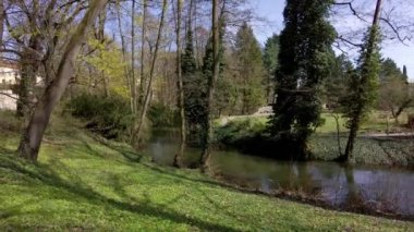 Çek Cumhuriyeti 'nin güneşli bir bahar gününde, Olomouc şehrindeki bir parkta, ağaçların arasında akan bir nehir yatağı.