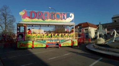 Bir sürü arabanın geçtiği güzel bir sokak manzarası. Bu yolun kenarında Ejderha adında küçük bir tezgah ve çocuklar için küçük bir gezinti görülebilir.