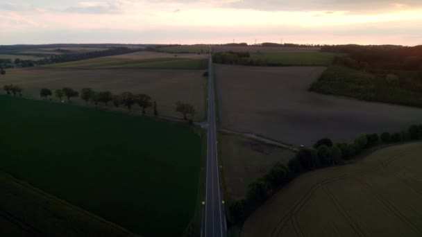 Samochody Przejeżdżające Cichą Długą Drogą Kierunku Zachodu Słońca Sylwetki Turbin — Wideo stockowe