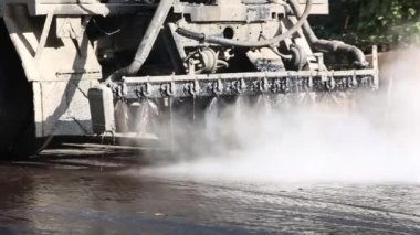 Yol arabası asfalta su döker.