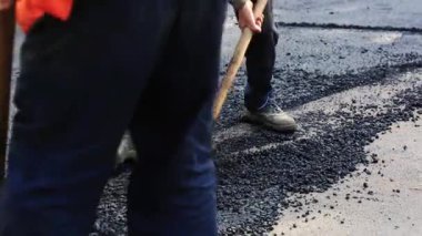 İşçi seviyesi, siyah karışım asfalt ve tırmık.