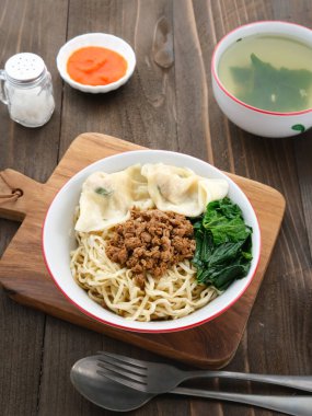 Mie Ayam Pangsit (Tavuk, Hamur köftesi ve sebzeli erişte) Endonezya 'nın popüler yiyeceğidir. Tahta masada kasede servis edilmiş. Seçici odak.