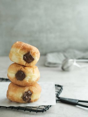 Çikolata dolgulu Bomboloni. Masadaki beyaz bir tabakta servis edilmiş. Bulanık arkaplan ve seçici odak resmi.