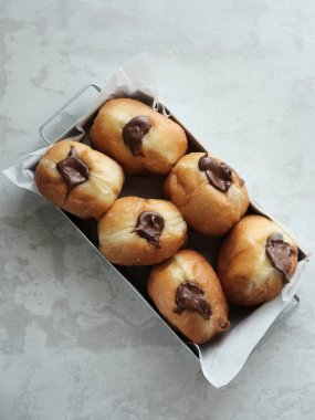 Çikolata dolgulu Bomboloni. Masadaki beyaz bir tabakta servis edilmiş. Bulanık arkaplan ve seçici odak resmi.