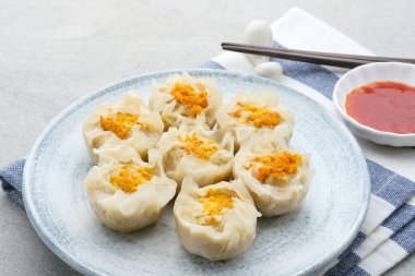 Lezzetli Dim Sum, tabakta servis edilen ev yapımı Çin mantısı, sos ve çubukla. Gri arkaplanda izole edilmiş, kapat.
