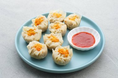 Lezzetli Dim Sum, tabakta servis edilen ev yapımı Çin mantısı, sos ve çubukla. Gri arkaplanda izole edilmiş, kapat.