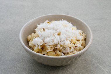 Grontol Jagung veya Corn grontol Endonezya 'da geleneksel bir atıştırmalıktır. Haşlanmış kabuklu mısır ve rendelenmiş hindistan cevizi. Gri arka planda bir kasede servis edilmiş. Seçici odak.