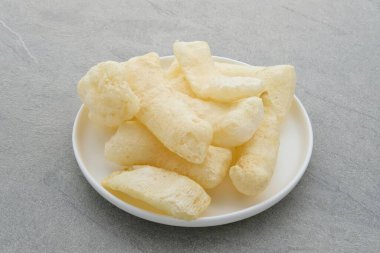 Rambak, ya da kerupuk kulit Endonezya 'nın geleneksel krakerleridir. Sığır derisinin yumuşaklığından yapılmıştır. Beyaz tabakta servis edilmiş. Gri arkaplanda izole.