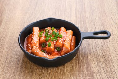 Tteokbokki veya Topokki, kızarmış pirinç keki çubuğu, popüler Kore sokak yemekleri baharatlı gochujang sosu ve susam tohumlu.. 