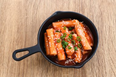 Tteokbokki veya Topokki, kızarmış pirinç keki çubuğu, popüler Kore sokak yemekleri baharatlı gochujang sosu ve susam tohumlu.. 