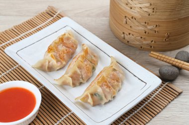 Un hamurundan yapılmış ve baharatlı tavukla doldurulmuş Kore Mandu böreği. Acı soslu bir tabakta servis edilir.