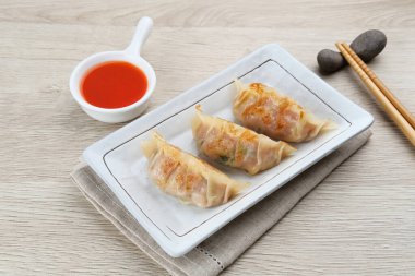 Un hamurundan yapılmış ve baharatlı tavukla doldurulmuş Kore Mandu böreği. Acı soslu bir tabakta servis edilir.