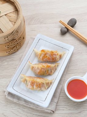 Un hamurundan yapılmış ve baharatlı tavukla doldurulmuş Kore Mandu böreği. Acı soslu bir tabakta servis edilir.