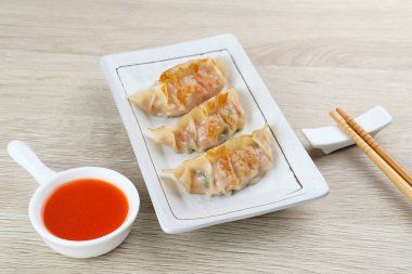 Un hamurundan yapılmış ve baharatlı tavukla doldurulmuş Kore Mandu böreği. Acı soslu bir tabakta servis edilir.