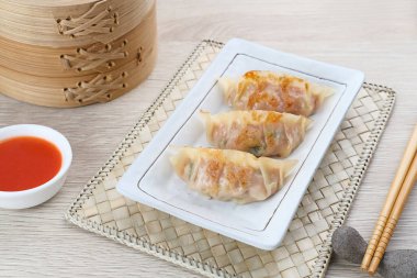 Un hamurundan yapılmış ve baharatlı tavukla doldurulmuş Kore Mandu böreği. Acı soslu bir tabakta servis edilir.