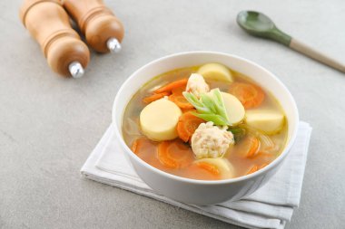 Yumurtalı tofu, havuç ve karides köfteli çorba. Gri arka planda beyaz kasede servis ediliyor..