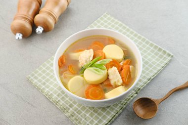 Yumurtalı tofu, havuç ve karides köfteli çorba. Gri arka planda beyaz kasede servis ediliyor..