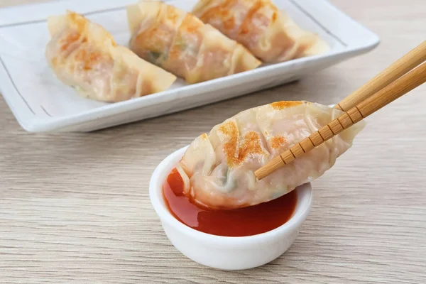 Un hamurundan yapılmış ve baharatlı tavukla doldurulmuş Kore Mandu böreği. Acı soslu bir tabakta servis edilir.