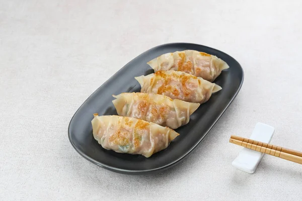 Un hamurundan yapılmış ve baharatlı tavukla doldurulmuş Kore Mandu böreği. Acı soslu bir tabakta servis edilir.