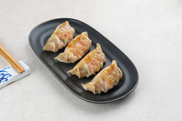 Un hamurundan yapılmış ve baharatlı tavukla doldurulmuş Kore Mandu böreği. Acı soslu bir tabakta servis edilir.