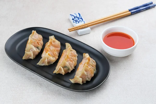 Un hamurundan yapılmış ve baharatlı tavukla doldurulmuş Kore Mandu böreği. Acı soslu bir tabakta servis edilir.