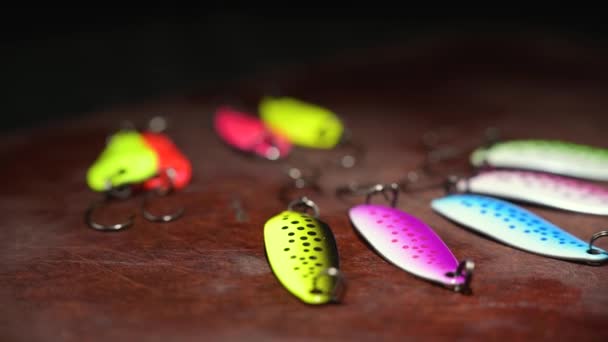 Spinners of different colors and shapes for fishing on a brown table. Background in blur. — Stock Video