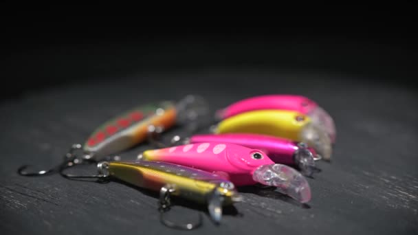 Rybaření návnady různých barev a tvarů pro rybolov na hnědém stole. Pozadí v rozostření. — Stock video