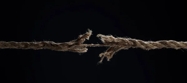 Uma corda esticada quebra em um fundo preto. O conceito de divórcio. Uma ruptura em um relacionamento. — Fotografia de Stock
