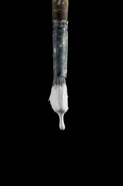 Paint brush with white colour isolated on black background. White paint drips from the brush. Photo with copy space. An old art brush. — Stock Photo, Image