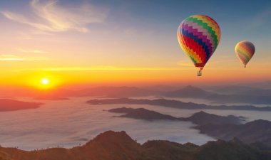 Renkli sıcak hava balonları dağın üzerinden uçuyor sisli sabah güneşi doğuyor 
