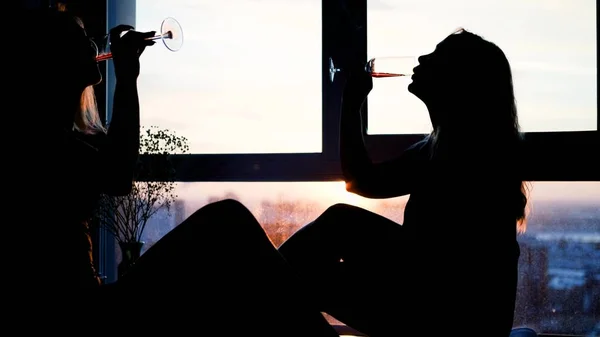 A fehérneműs barátnők pezsgőt isznak, miközben habos fürdő és rózsaszirmok mellett ülnek. — Stock Fotó