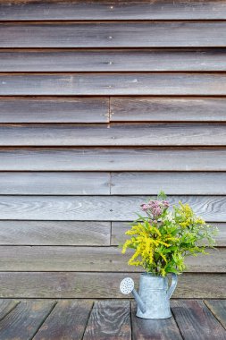 Tahta bir duvarın önündeki tahta bir yüzeyde, kopyasal uzay ve dikey görüş alanı olan kır çiçekleri.
