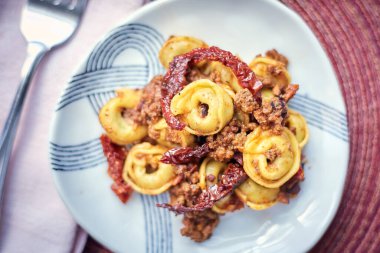 Bolonez soslu Tortellini ve çatal ve peçeteli kurutulmuş domatesler, yakın plan.