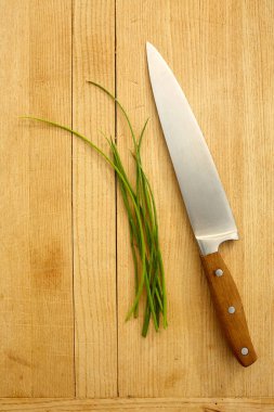 Kesme tahtasındaki taze soğanlı mutfak bıçağı.
