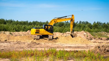 Bir kum havuzu ocağında endüstriyel sarı bir kazıcı gelişiyor. Sanayi, teknoloji, madencilik. Ağır endüstriyel makineler.