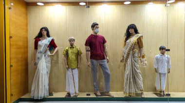 Yetişkin ve çocuk boylarında mankenler, bir giyim mağazasının önündeki cam bir kutunun içinde sergileniyor.