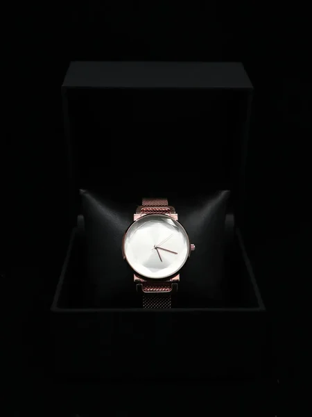 women's luxury analogue watch, rose gold in color placed inside a black box isolated in a black background