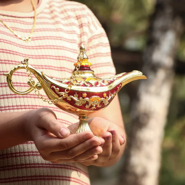 a gold magic lamp said to be holding a genie inside in fantasies in the palms of a kid