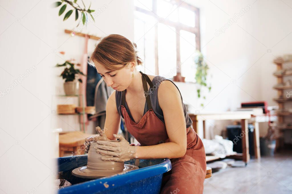 Shot of a woman molding clay on a pottery wheel