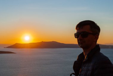 Yunanistan 'ın Santorini kentinde günbatımının arka planında bir adamın kafası ve omuzlarının silueti.
