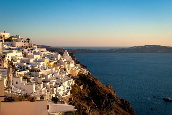 Fira in the rays of the setting sun. Santorini, Greece.