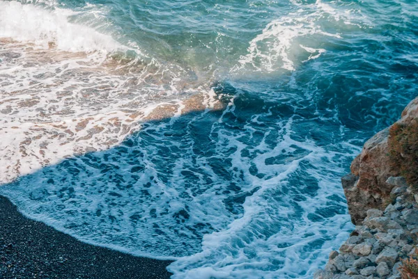 Волны, скалы и черный песок на пляже Камари, Санторини, Греция — стоковое фото