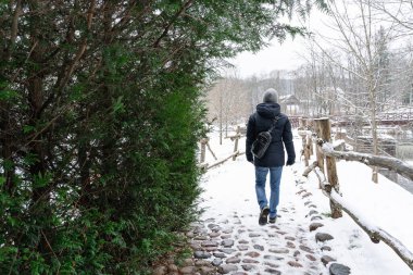 A man walks on snow-covered paving stones in the countryside
