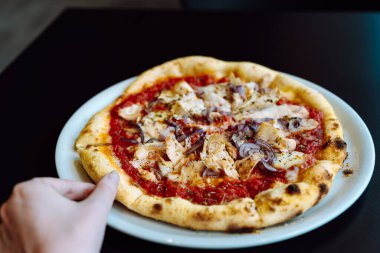 Elin bir dilim pizzayı tavukla birlikte tabaktan alır..