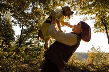 Mutlu ev sahibi oynuyor, sonbahar sezonunda dışarıda arı kostümü giyen köpeğini havaya fırlatıyor..
