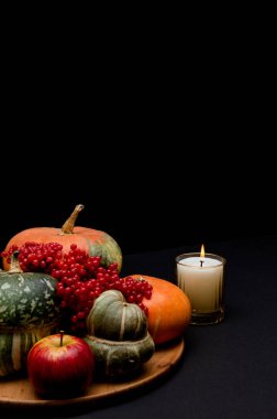 Siyah arka planda mum olan Şükran Günü balkabağı kompozisyonu. 