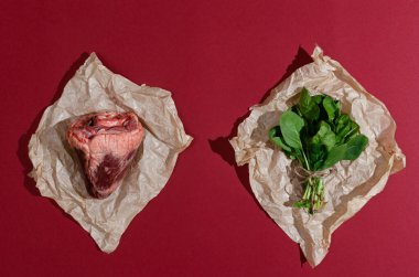 Gerçek bir hayvanın kalp eti ve ıspanağı kağıt üzerinde ve kırmızı bordo arka planda yaratıcı düzlükte..