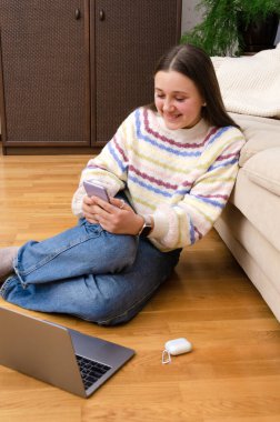 Akıllı telefon kullanan mutlu blogger kızı, sosyal medya için görüntülü konuşma. Evde dizüstü bilgisayarla ders çalışmak.