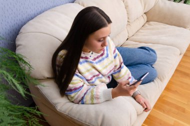 Çevrimiçi akıllı telefon aygıtı üzerinde sosyal medyada gezinen konsantre genç kız. 